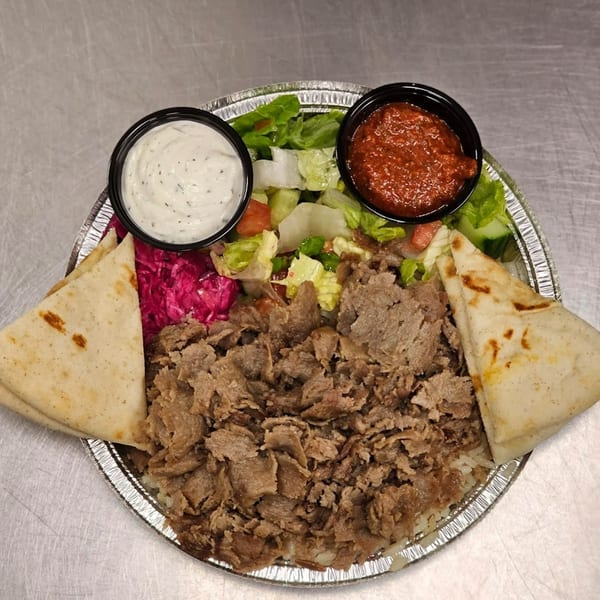 Kapadokia Grill's Mediterranean Turkish platter with sliced meat, rice, salad, pita, and two sauces.