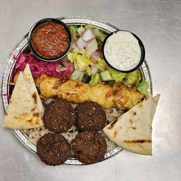 Kapadokia Grill's Mediterranean platter with chicken skewer, falafel, rice, salad, pita bread, and two sauces.